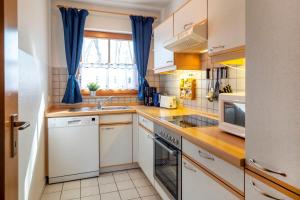 una cocina con electrodomésticos blancos y cortinas azules en Ferienpark Freesenbruch Wohnung 1 1 - Seestern, en Zingst