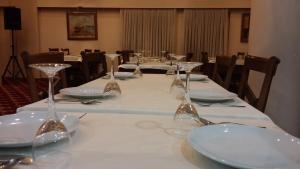 una mesa larga con platos blancos y vasos. en Ozilhan Hotel, en Ankara