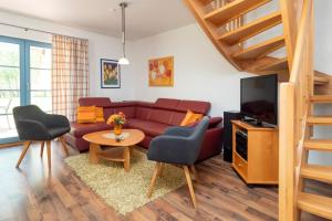 ein Wohnzimmer mit einem Sofa und einem TV in der Unterkunft Ferienpark Freesenbruch Doppelhaushälfte 12 - Sommerlust in Zingst