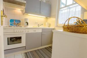 a kitchen with white appliances and a basket on the counter at Appartementhaus Boddenblick "Himmelkieker" in Zingst
