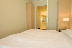 ein weißes Bett in einem Zimmer mit Spiegel in der Unterkunft Haus Seeblick Wohnung 326 in Zingst