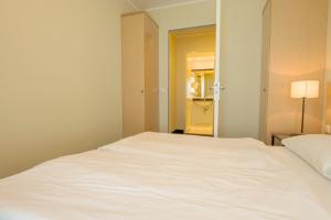 a white bed in a room with a mirror at Haus Seeblick Wohnung 326 in Zingst