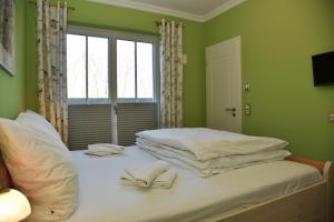 1 dormitorio con paredes verdes y 1 cama con toallas. en Logierhaus Friedrich WE 2 - "Gödeke Michels", en Zingst