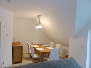a dining room with a wooden table and white chairs at Hafenstrasse 15 Kieckut in Prerow in Prerow
