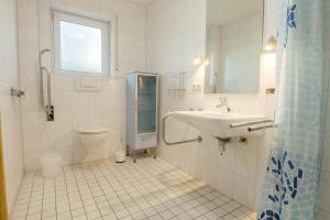 a white bathroom with a sink and a toilet at Nautilus in Zingst