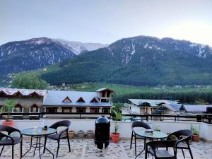 a patio with tables and chairs with mountains in the background at Manali residency in Manāli