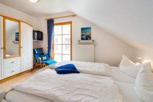 a bedroom with a white bed and a chair at Ferienpark Freesenbruch Reihenhaus 6 - Delfin in Zingst +30 photos