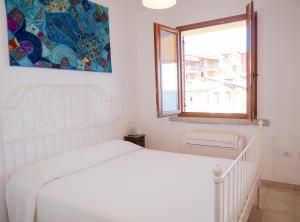 a white bedroom with a white bed and a window at La Casa Del Mare Tanca Piras in Nebida