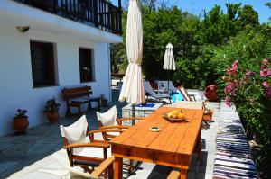 un patio con mesa de madera, sillas y sombrillas en Alikias Country House, en Panormos Skopelos