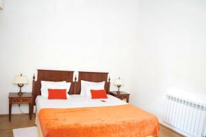 een slaapkamer met een bed met oranje lakens en 2 tafels bij Mosteiro De S. Cristovao De Lafoes in São Cristóvão de Lafões