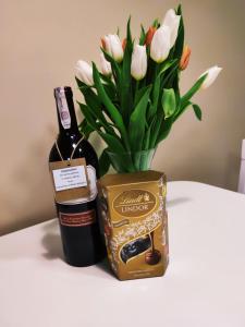 eine Flasche Wein und eine Vase mit Blumen in der Unterkunft Domek letniskowy Elizjum in Myczków + 17 Fotos