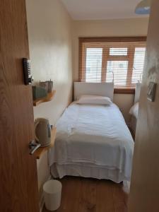a bedroom with a white bed and a window at Celtic House in Merthyr Tydfil