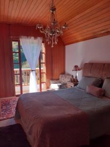 a bedroom with a large bed and a chandelier at Casa no Capivari in Campos do Jordão