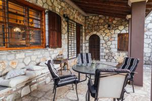eine Terrasse mit Tisch und Stühlen auf einer Steinmauer in der Unterkunft Villa Polytimi in Vónitsa