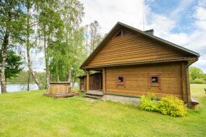a wooden cabin in a field with a grass yard at Pas Kaziuką namas-sodyba in Ignalina