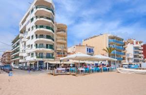 a beach with tables and umbrellas and a building at LG Sea Views in Calafell