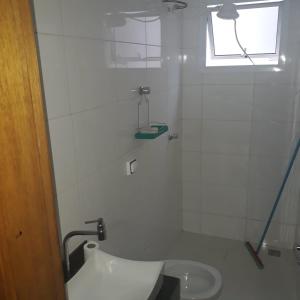 a white bathroom with a toilet and a window at Quartos Uberlandia in Uberlândia