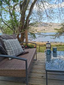 a wooden deck with a bench and a table at The bay ,luxury shepherds hut, in Dundonnell