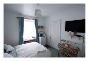 a bedroom with a bed and a table and a television at Cornmill House, With Outstanding Sea Views In Garlieston in Garlieston