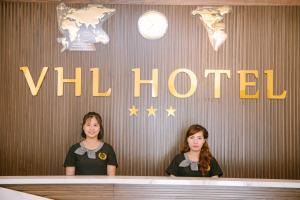 two women standing in front of a wall with the word will hotel at Khách sạn VHL Hà Nam in Phủ Lý