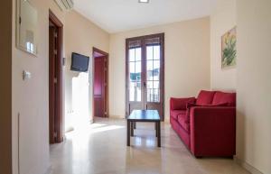 ein Wohnzimmer mit einem roten Sofa und einem Tisch in der Unterkunft Rey de Sevilla Flats - Macarena in Sevilla