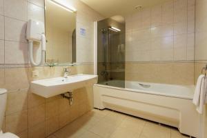 a bathroom with a sink and a tub and a toilet at Alka Boutique Apartments & SPA in Palanga