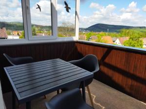 een tafel en stoelen in een kamer met ramen bij Ferienwohnung Harz Valley -Mit Fernblick in den Harz. in Goslar