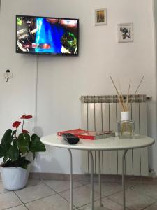 - une table blanche avec une télévision murale dans l'établissement Fiori e farfalle apartment, à Caprarola