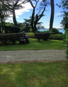 a park with benches and flowers in the grass at Les Hortensias grande tente familiale 2 chambres et séjour sur camping familial près des plages in Plestin-les-Grèves
