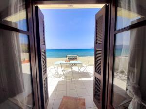 una porta aperta sulla spiaggia con tavolo e sedie di Waves House a Kíssamos