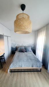 a bedroom with a bed and a chandelier at Apartament Dobra Fala in Gdańsk
