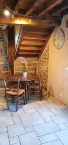 uma sala de jantar com mesa e cadeiras e um relógio em Gite Le Morvan em Lormes