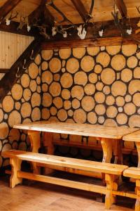 einen Holztisch und Bänke in einem Zimmer mit Holzscheiten in der Unterkunft Котедж з неймовірними краєвидами in Slawske