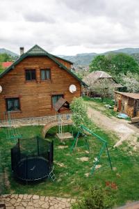 ein Holzhaus mit einem Spielplatz davor in der Unterkunft Котедж з неймовірними краєвидами in Slawske