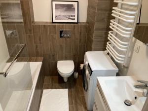 La salle de bains est pourvue de toilettes, d'un lavabo et d'une douche. dans l'établissement Apartament Łagiewniki, à Cracovie