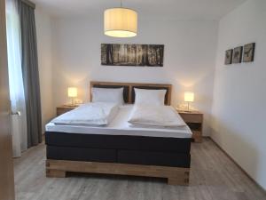 1 dormitorio con 1 cama con 2 mesitas de noche y 2 lámparas en Landhaus Kirchmair, en Telfes im Stubai