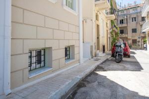 a red scooter parked in an alley next to a building at IPELHOME - Rodi Boutique Apartment in Athens