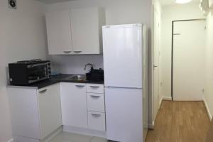 a kitchen with white cabinets and a white refrigerator at Private Studio home away from home ... in Hackbridge