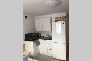 a kitchen with white cabinets and a refrigerator at Private Studio home away from home ... in Hackbridge