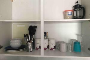 a kitchen shelf with dishes and utensils on it at Private Studio home away from home ... in Hackbridge