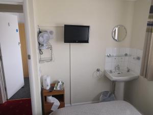 a bathroom with a sink and a tv on the wall at Seashells Guest House in Great Yarmouth