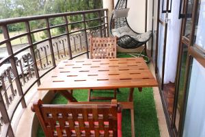 - Balcón con mesa de madera y 2 sillas en Glamour Suites, en Nanyuki