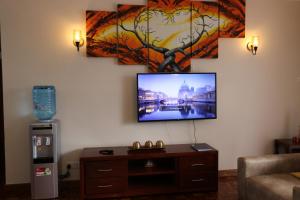 sala de estar con TV de pantalla plana en la pared en Glamour Suites, en Nanyuki