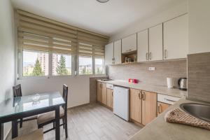 eine Küche mit weißen Schränken und einem Tisch mit einer Spüle in der Unterkunft Renta stan apartman odmor in Podgorica
