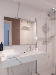 een witte badkamer met een wastafel en een spiegel bij Hotel Byron in Lerici