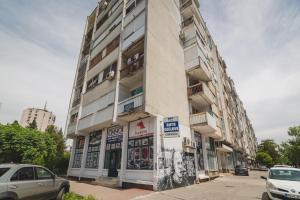 wysoki budynek z samochodami zaparkowanymi przed nim w obiekcie Renta stan apartman odmor w mieście Podgorica