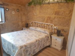 a bedroom with a bed and a stone wall at A Casiña do Xastre in Pontevedra