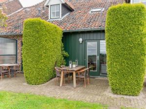 VoerendaalにあるApartment in Ubachsberg near Trailsの背の高い茂みのある家の前に置かれたテーブルと椅子
