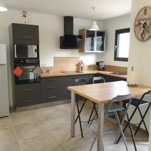 a kitchen with a wooden table and a dining room at Villa Leku Lucia 8 pers piscine chauffée 15 min plage en voiture in Sainte-Lucie de Porto-Vecchio