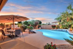 een terras met een tafel en een parasol naast een zwembad bij Sunset Ridge in Phoenix